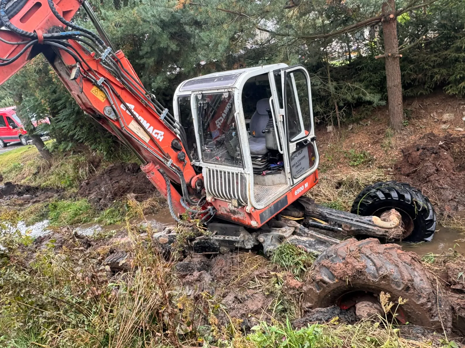Červený bagr vybírá sediment z koryta potoka v Dolní Dobrouči